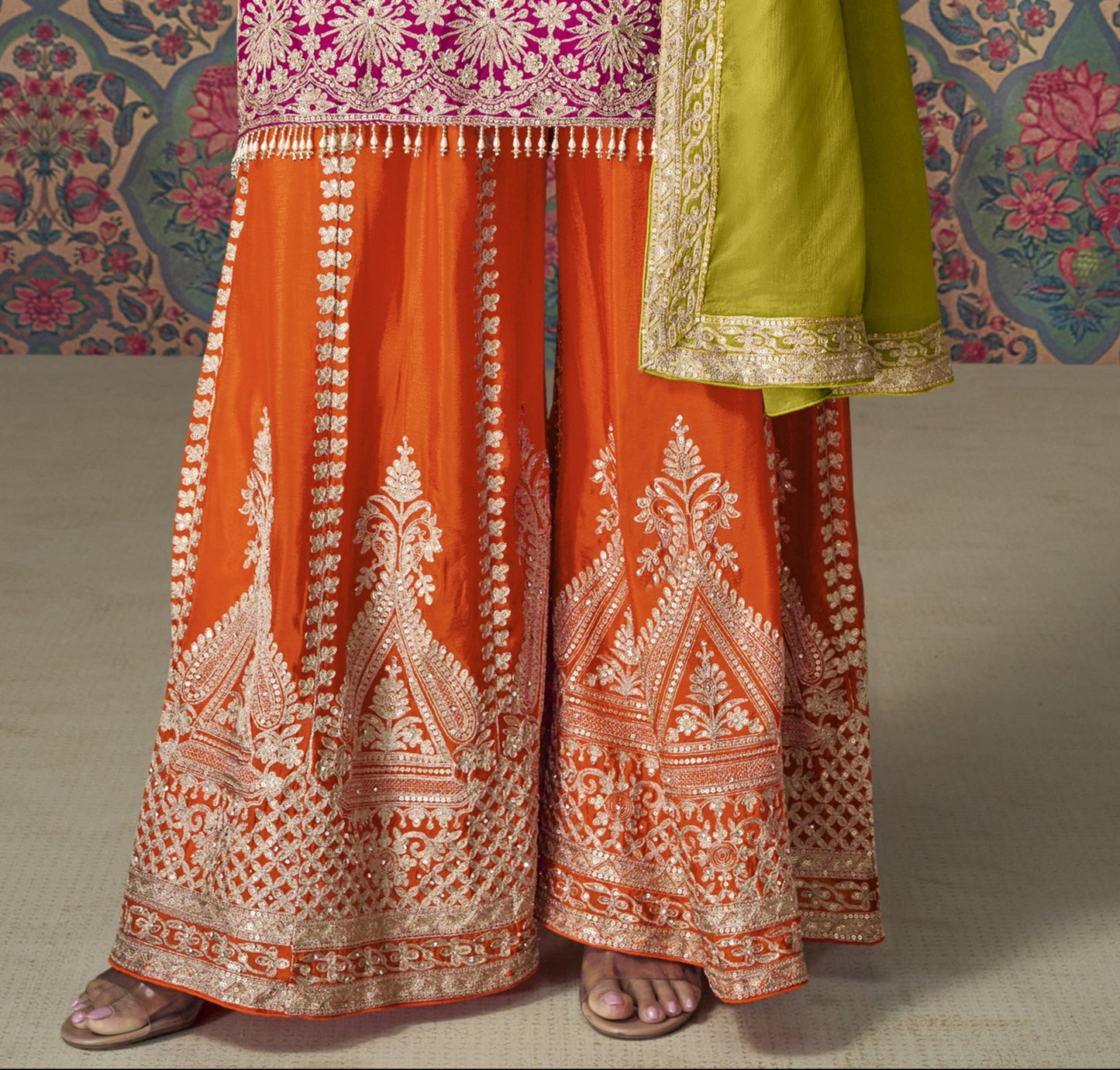Pink color palazzo suit with embroidery work, paired with orange palazzo and a contrasting green dupatta, offering a vibrant and festive fusion perfect for traditional celebrations.