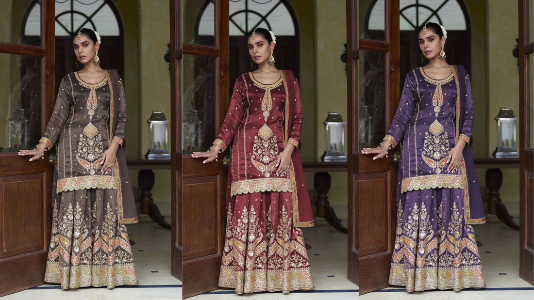 Three women wearing intricately embroidered ethnic sharara sets in brown, purple, and maroon, posing elegantly in a traditional doorway
