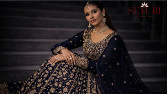 “Luxury navy blue embroidered lehenga with gold detailing styled on stone staircase, designer Indian wear”