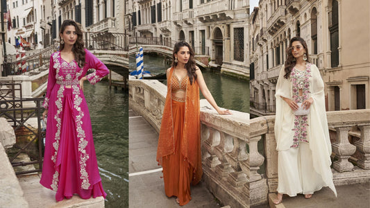 Three women pose along a Venetian canal wearing vibrant Indo-Western outfits in fuchsia, burnt orange, and ivory, each featuring intricate embroidery and flowing silhouettes.