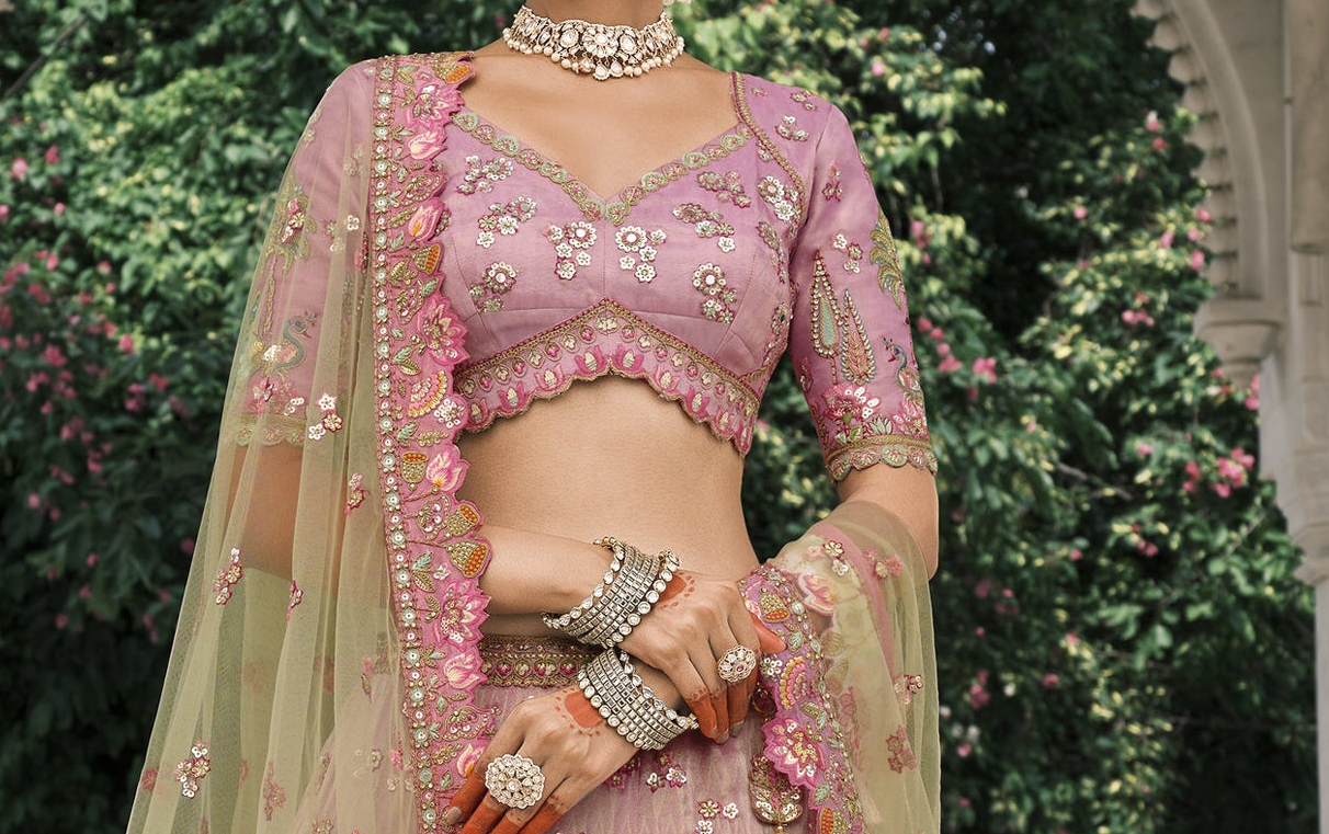 Close-up of an intricately embroidered designer blouse showcasing detailed handwork, shimmering sequins, rich zari patterns, and luxurious fabric texture