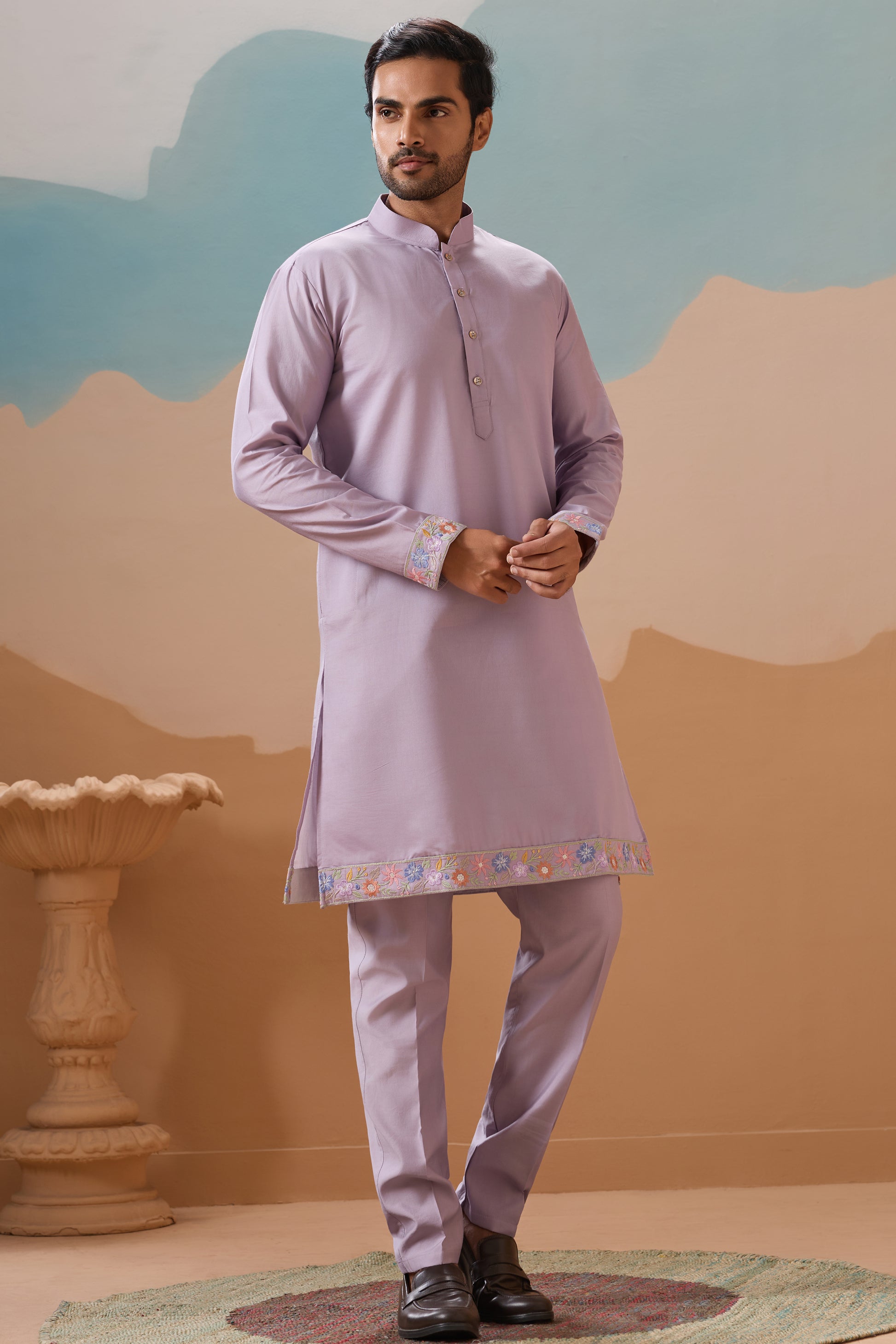 Man Wearing a Light Purple Kurta With White Pants Against A Scenic Background

