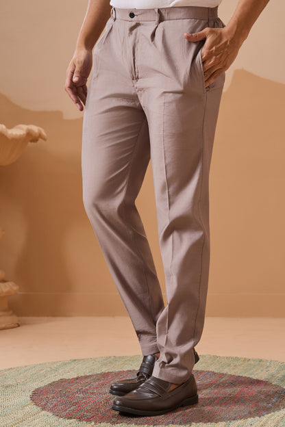 Person wearing beige pants standing on a textured surface with a neutral background

