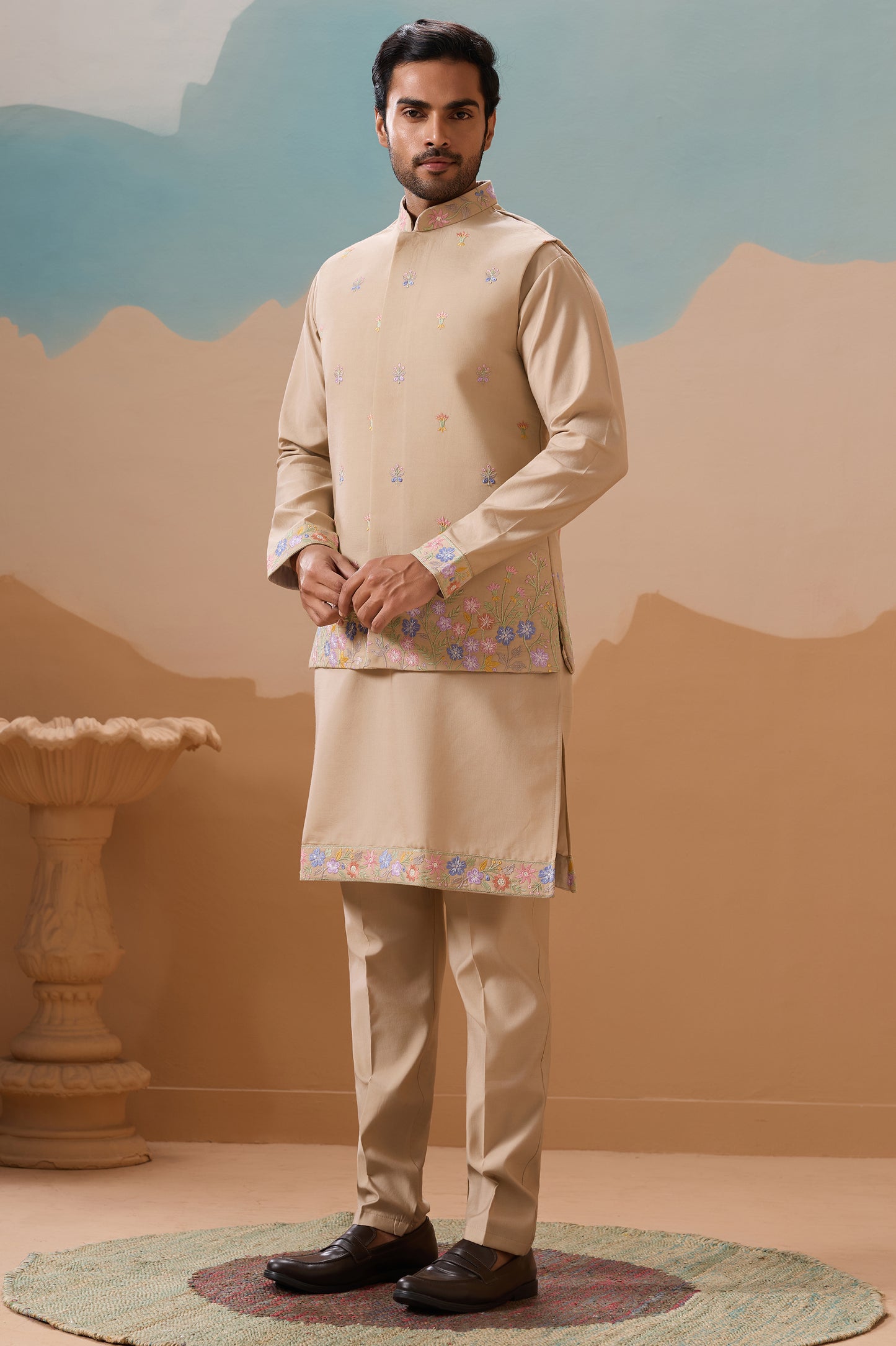 Man wearing a traditional beige kurta with embroidery against a neutral background
