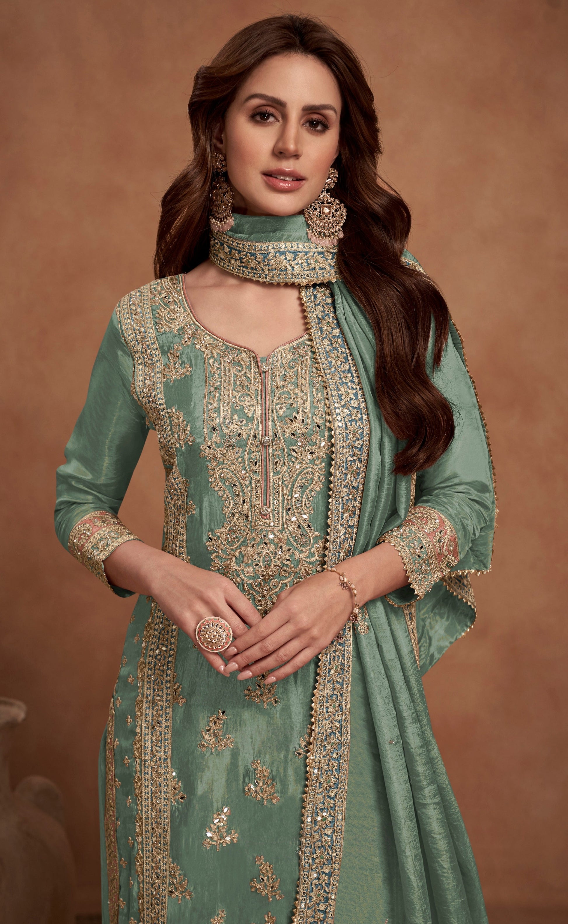 A Woman Wearing a Green and Gold Pakistani Salwar Kameez with Heavy Embroidery and Dupatta.