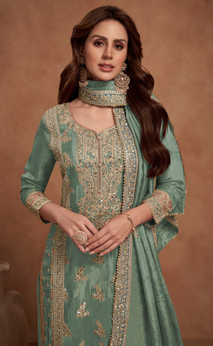 A Woman Wearing a Green and Gold Pakistani Salwar Kameez with Heavy Embroidery and Dupatta.
