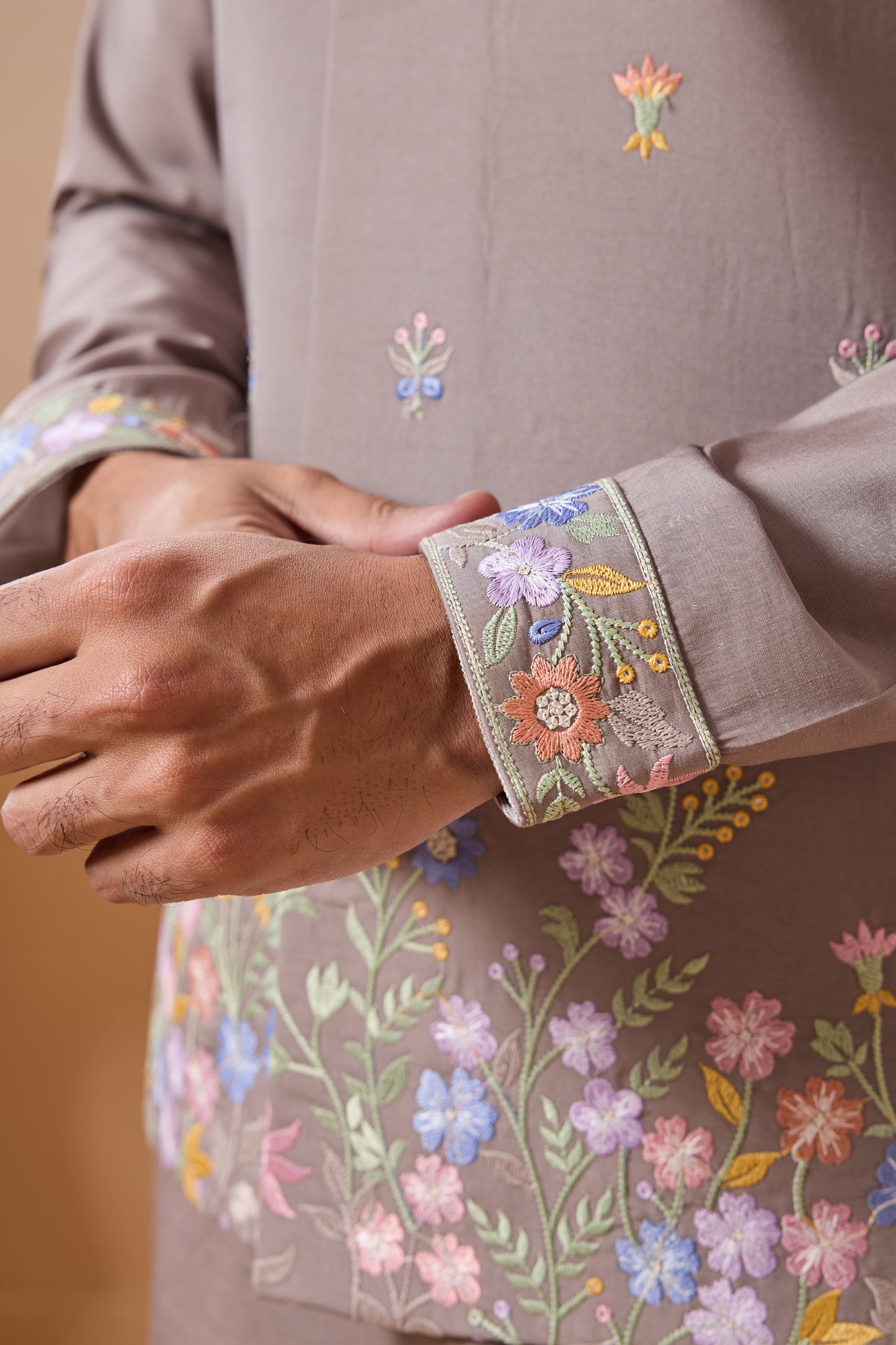 Close-up of a garment with floral embroidery on a beige background

