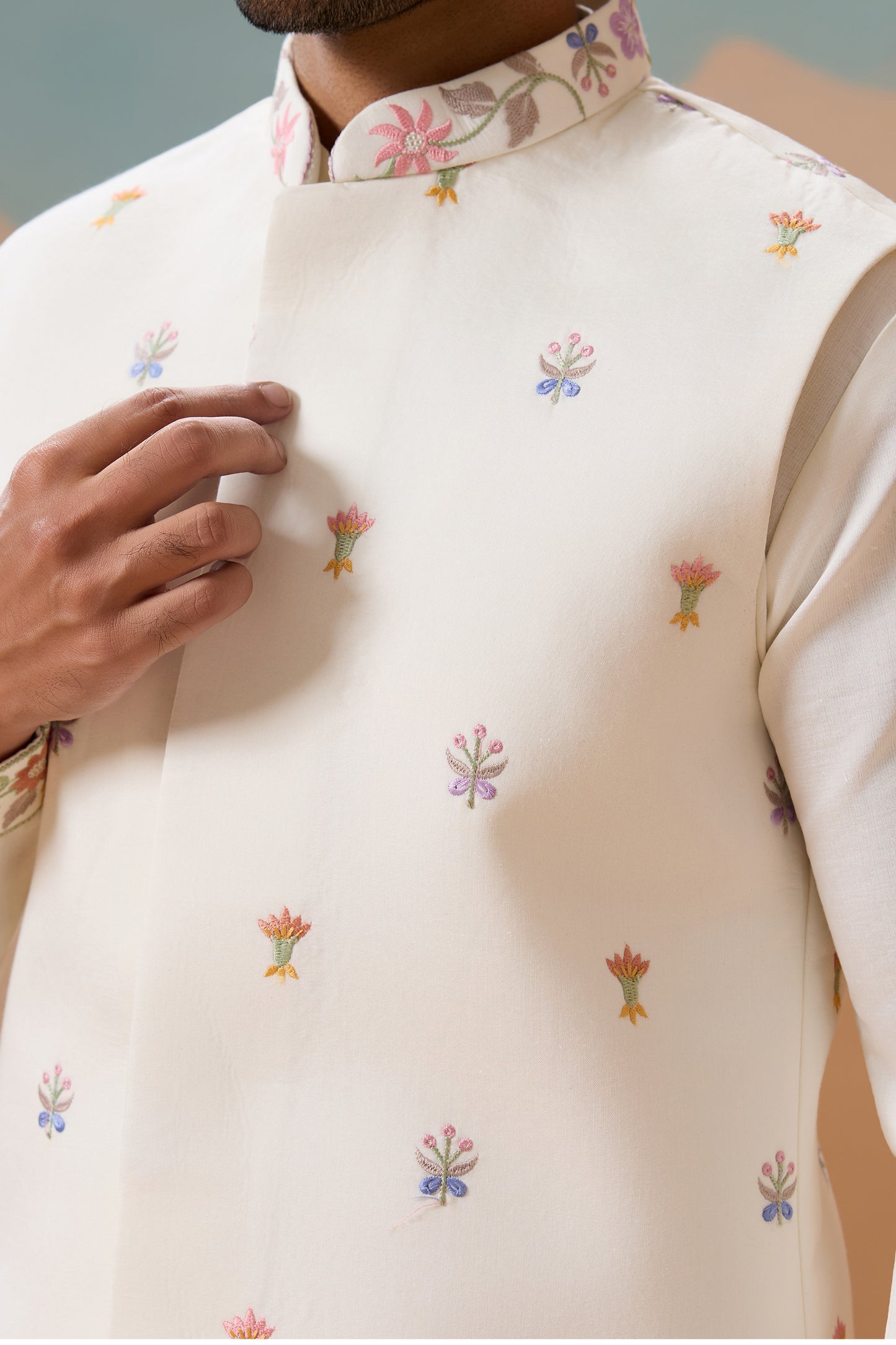 Close-Up of A Cream-Colored Embroidered Vest With Foral Patterns On A Neutral Background

