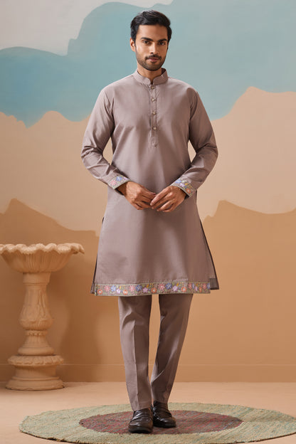 Man wearing a traditional kurta with a decorative hem against a scenic background

