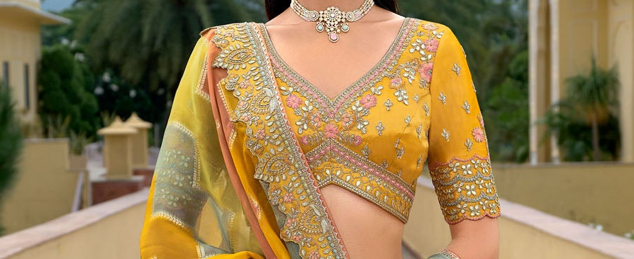 Close-Up Detail Of Mirror Work And Embroidery On Yellow Lehenga Choli For Haldi Ceremony