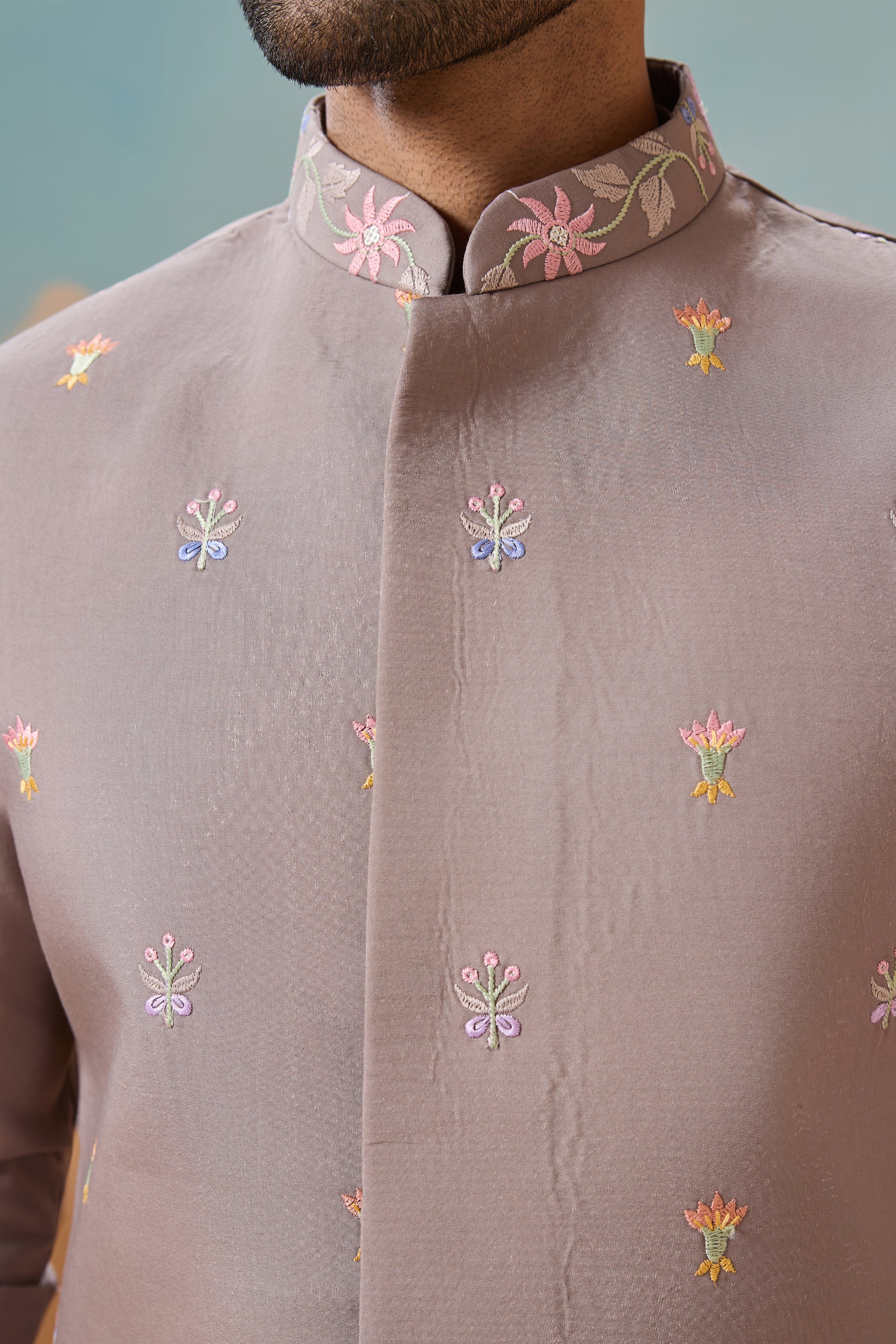 Close-up of a brown traditional outfit with floral embroidery on a blurred background
