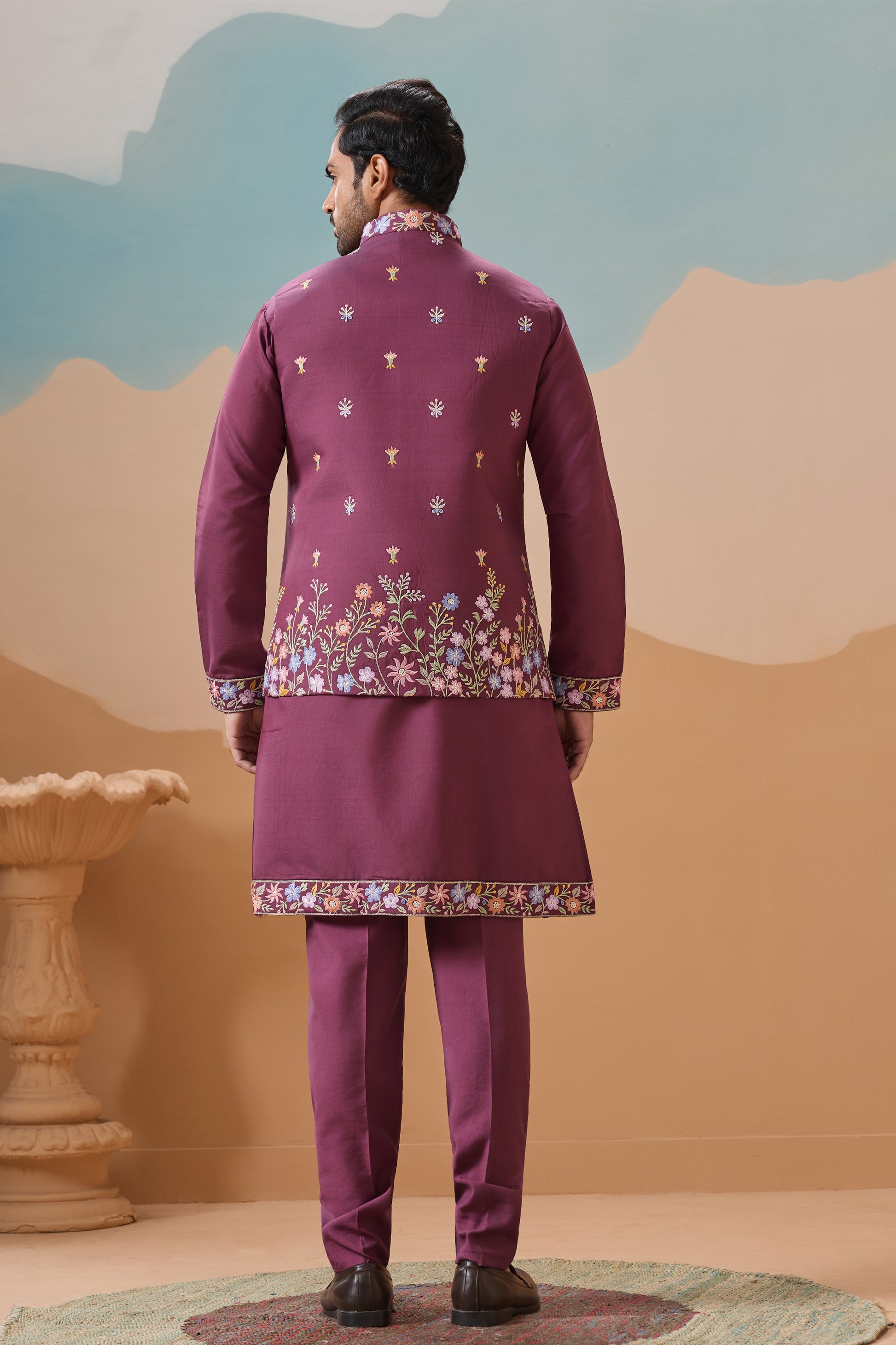 Man wearing a traditional Pink sherwani with floral patterns against a scenic background