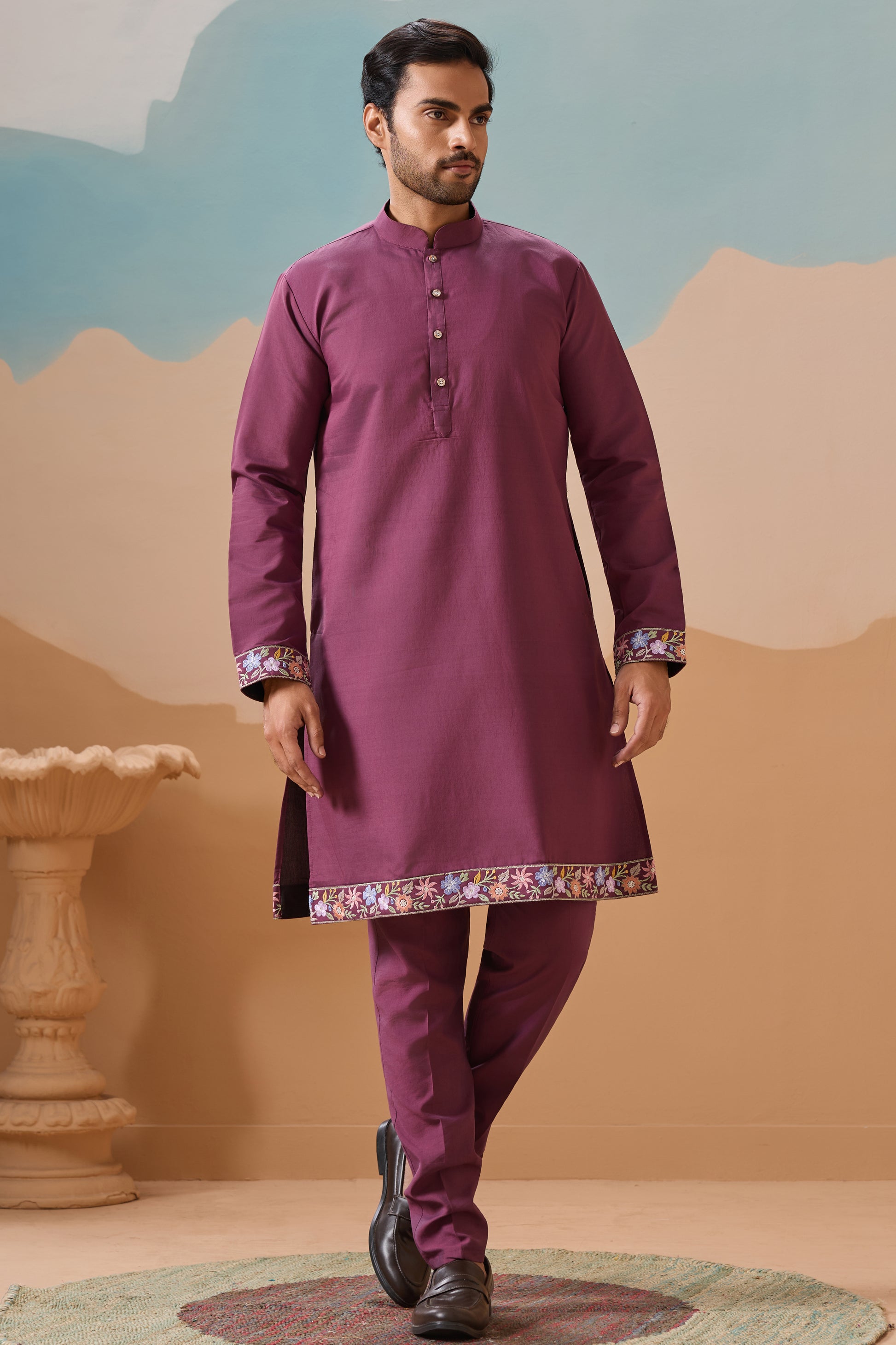 Man Wearing a Pink Kurta With pants against a desert-themed background

