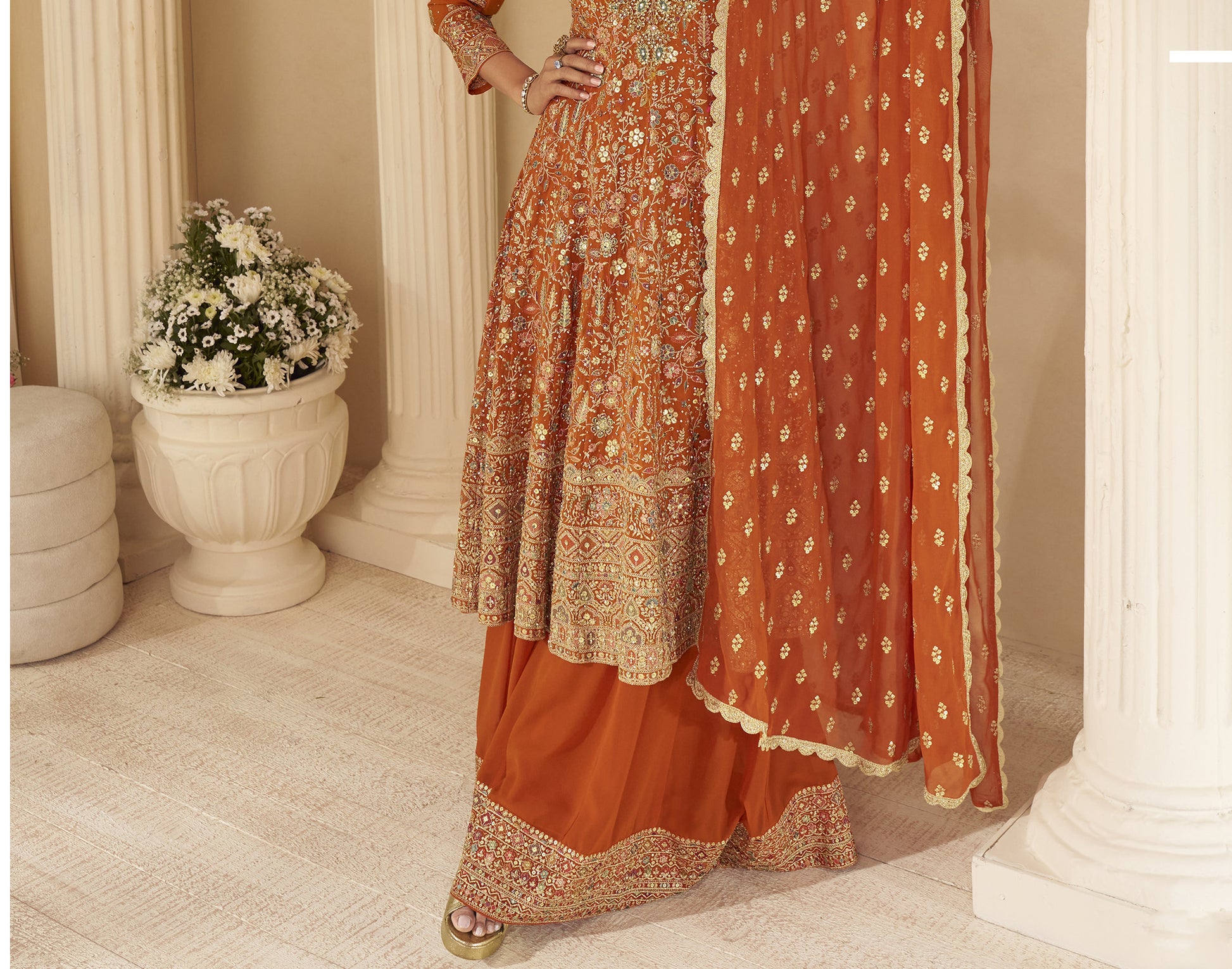 Indian ethnic rust orange outfit featuring intricate embroidery and flared sharara pants