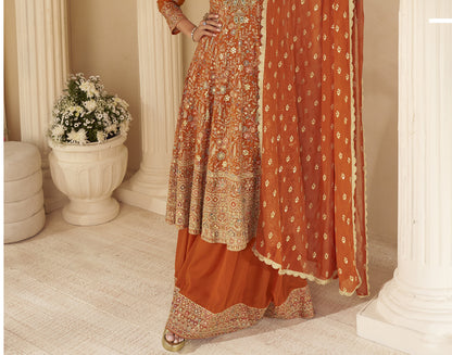 Indian ethnic rust orange outfit featuring intricate embroidery and flared sharara pants
