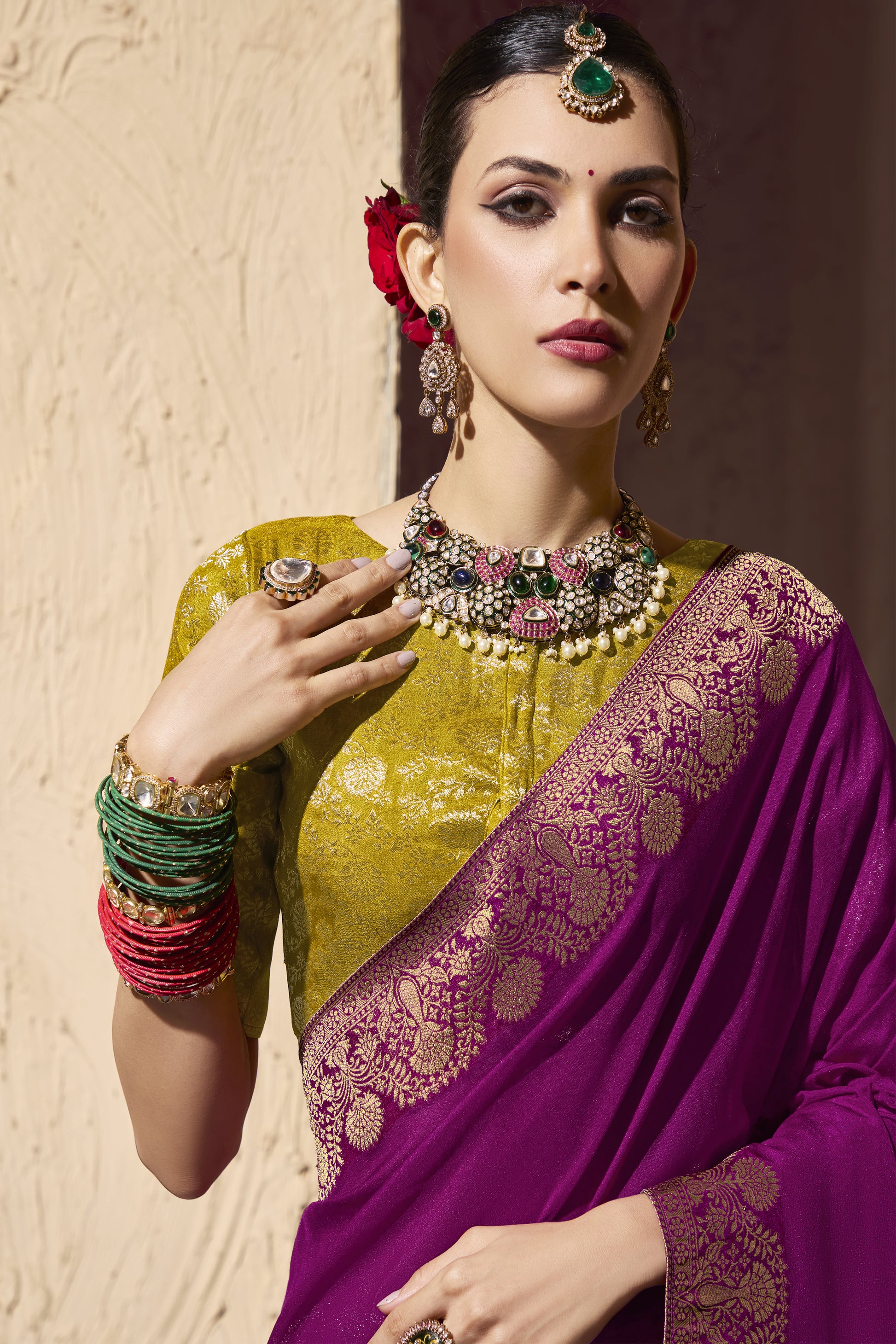 Woman wearing a golden and pink saree with jewelry.