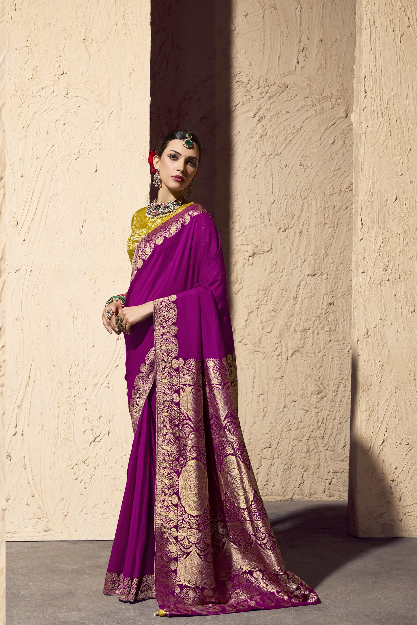 Woman wearing a pink saree with gold patterns with a side view

