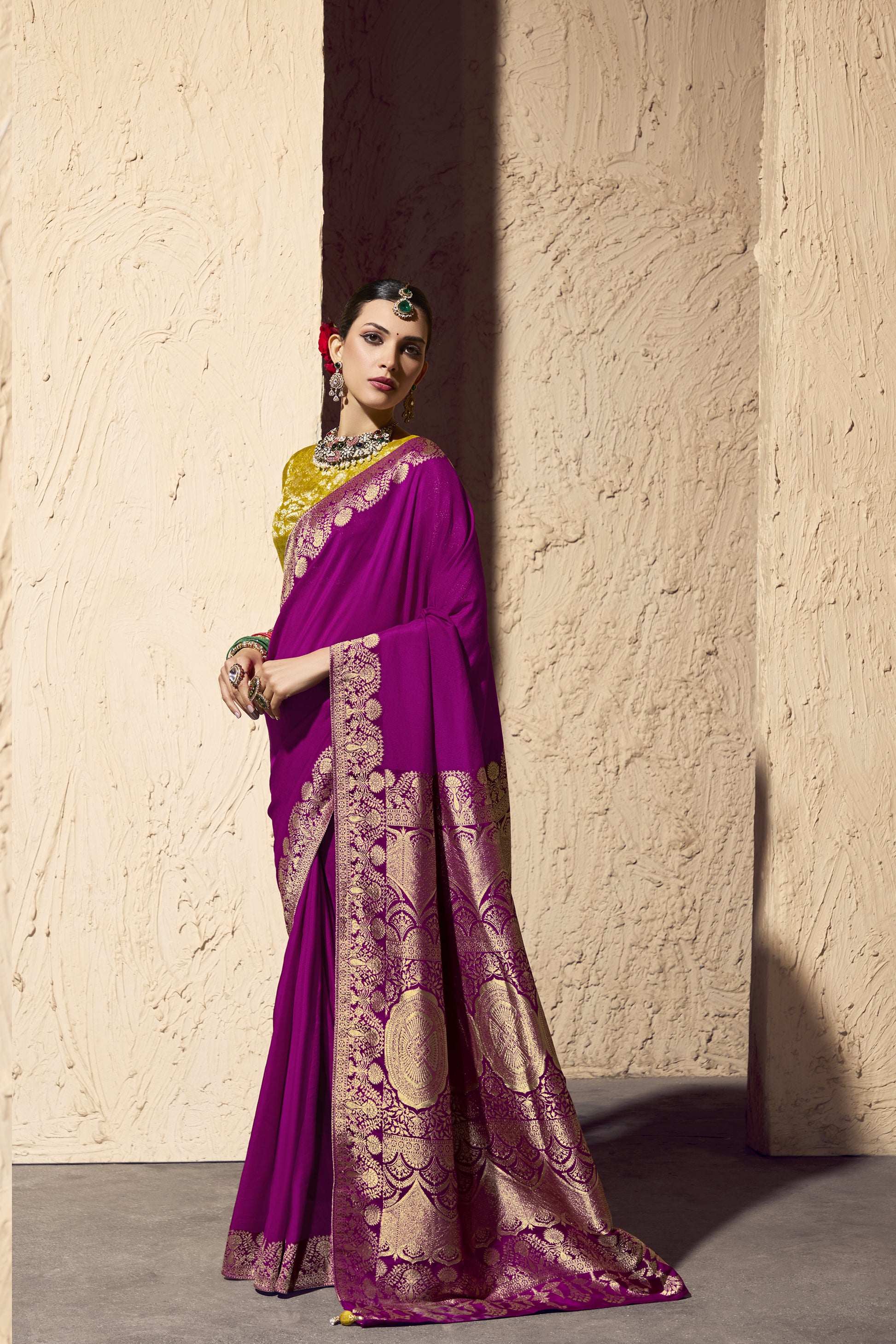 Woman wearing a pink saree with gold patterns with a side view
