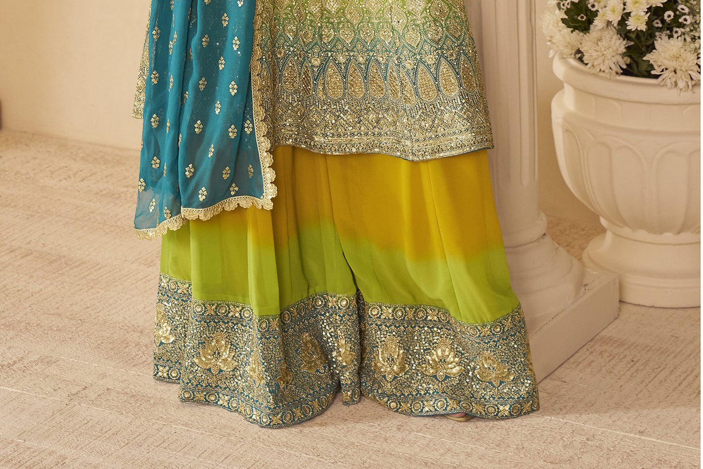 Traditional outfit with a gradient of blue, green, and yellow colors on a beige floor.