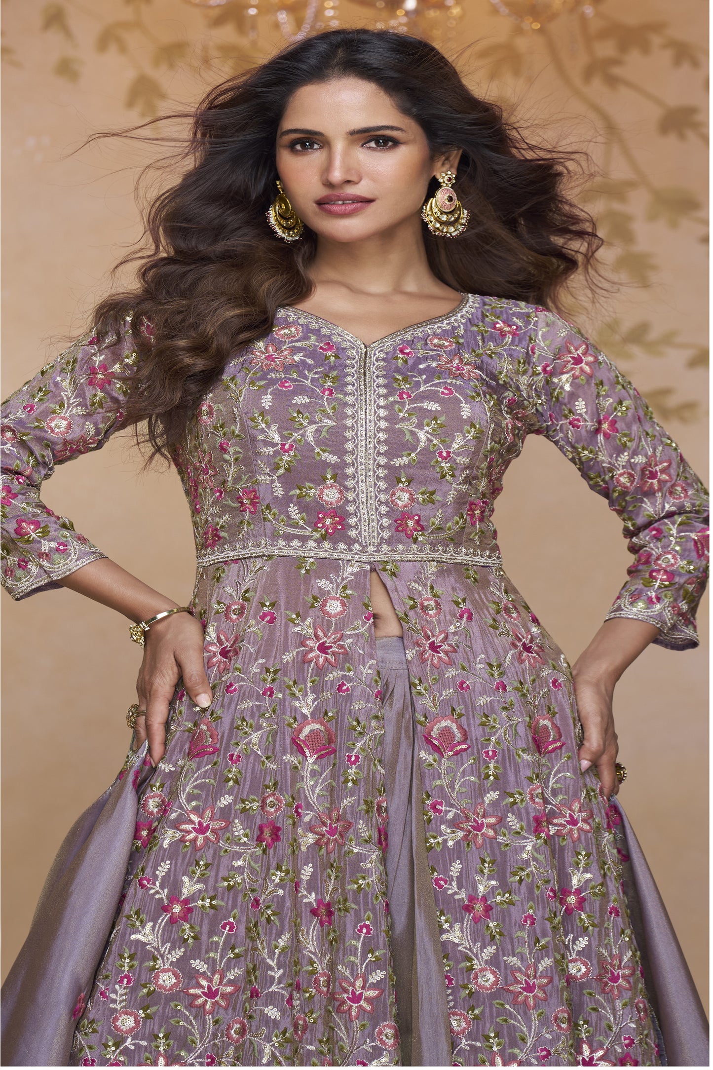Elegant mauve-purple full-length gown with heavy ethnic embroidery paired with statement earrings in a palace-themed setting