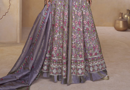 Elegant mauve-purple full-length gown with heavy ethnic embroidery paired with statement earrings in a palace-themed setting