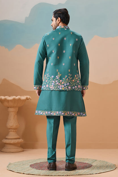 Man Wearing A Traditional Teal Outfit With Floral Patterns Against A Scenic Background

