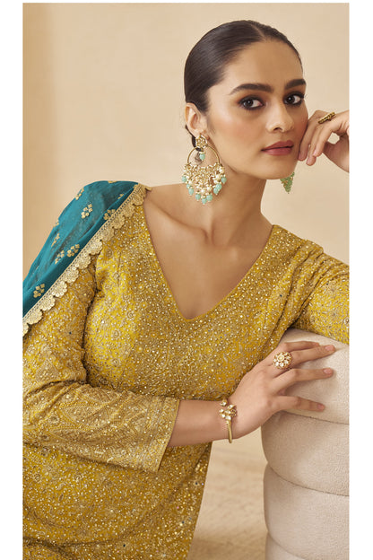 Woman wearing yellow ombré embroidered sharara suit with teal dupatta, designer ethnic wear.