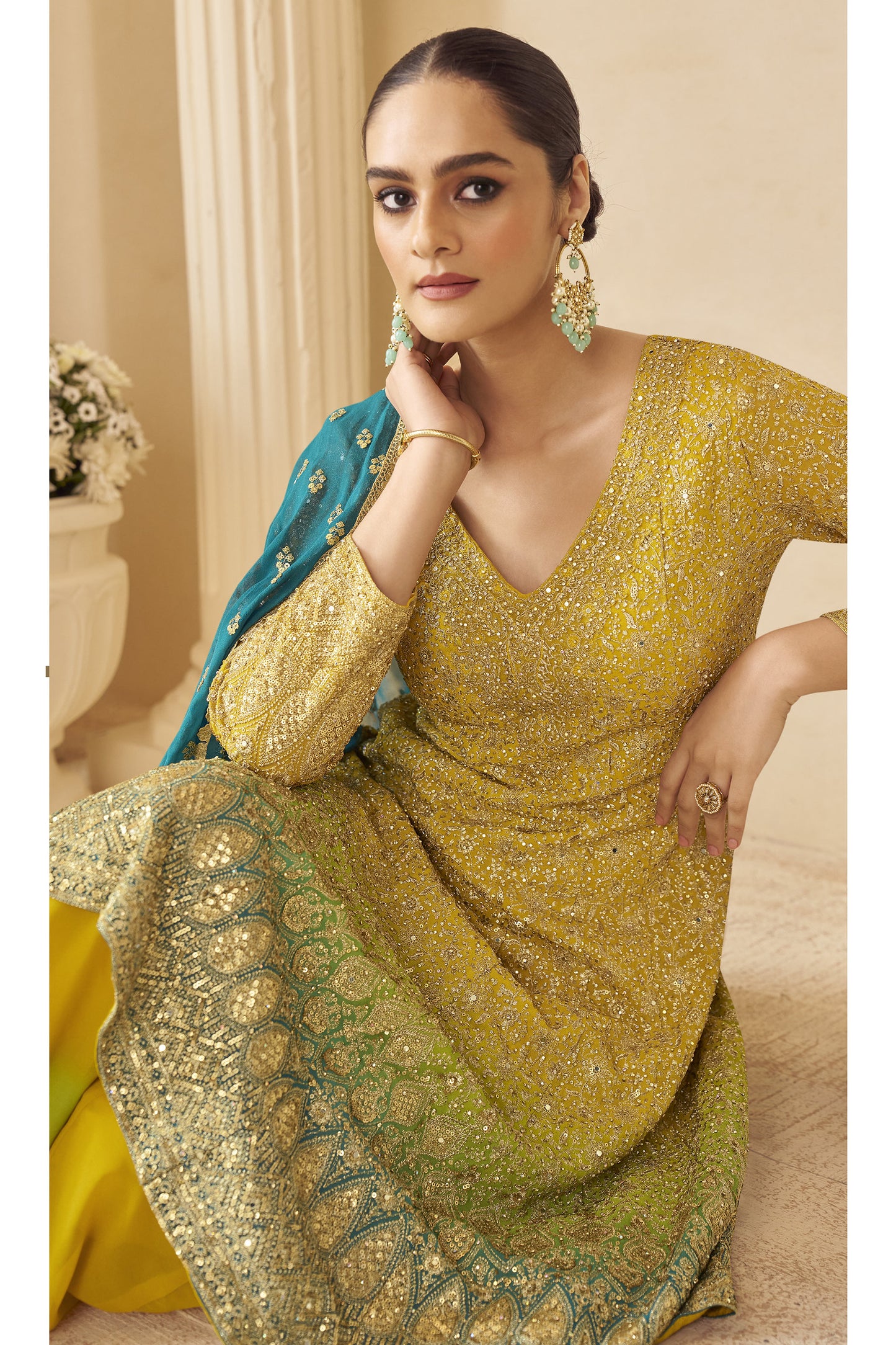 Woman in a yellow and green embroidered traditional outfit with a blue dupatta.